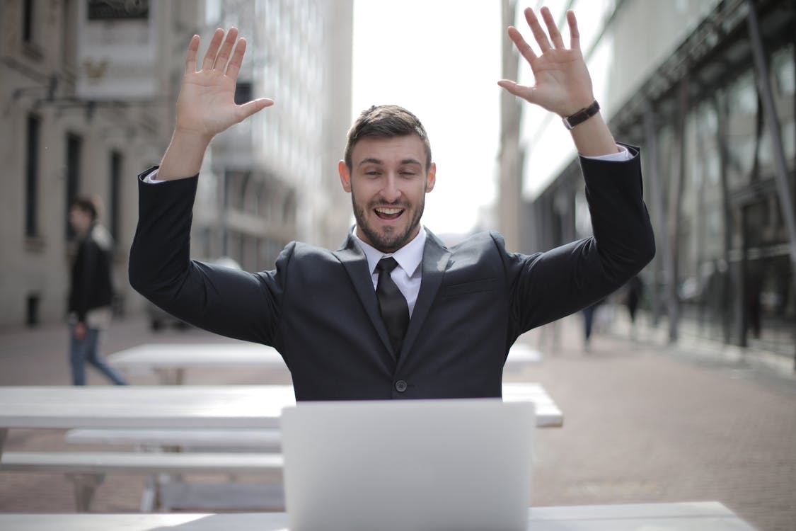 A man cheering and looking at a laptop screen after getting their dream job
