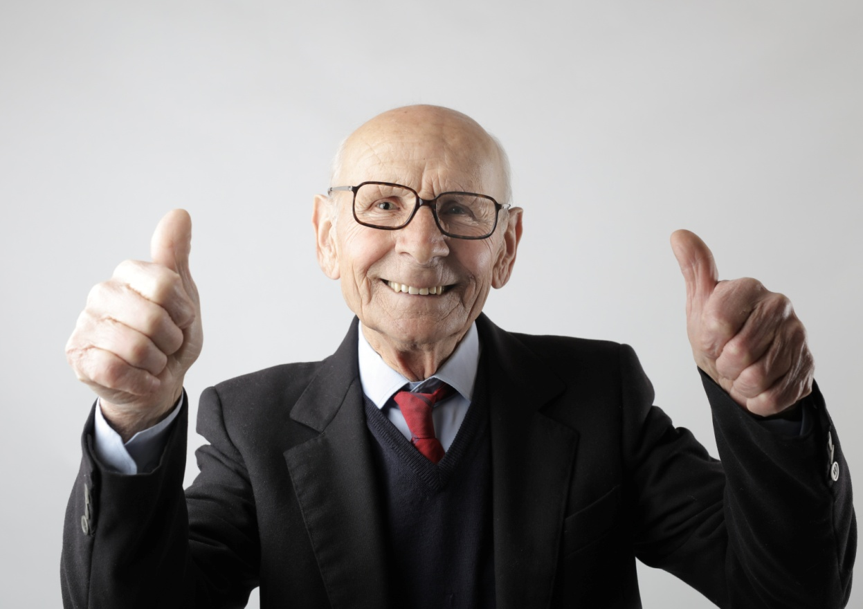 A man in a suit and tie with two thumbs up